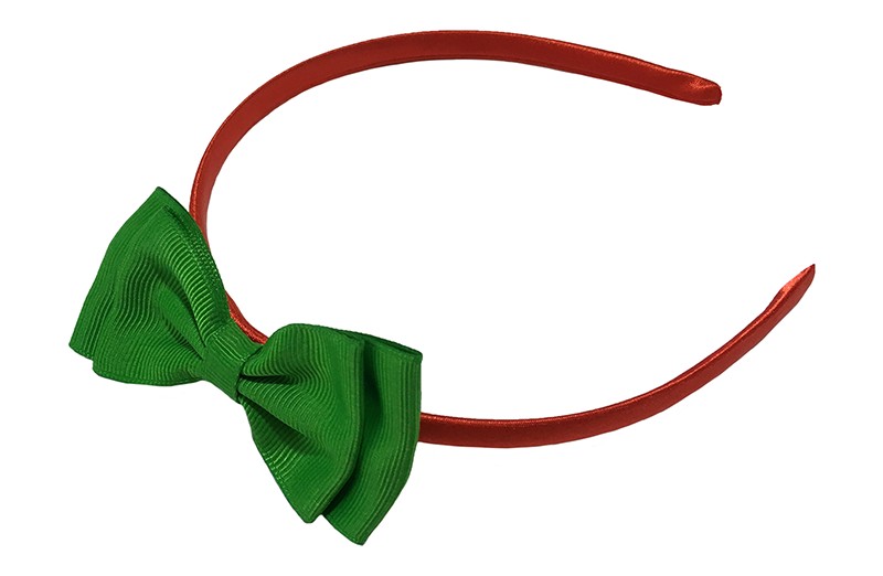 Vrolijke rood groene meisjes diadeem. Bekleed met glanzend rood  lint. Met daarop een dubbellaagse strik van groen lint. 
De diadeem is zonder tandjes. Het strikje is ongeveer 8 centimeter breed.
Geschikt voor ongeveer 2 - 6jaar.