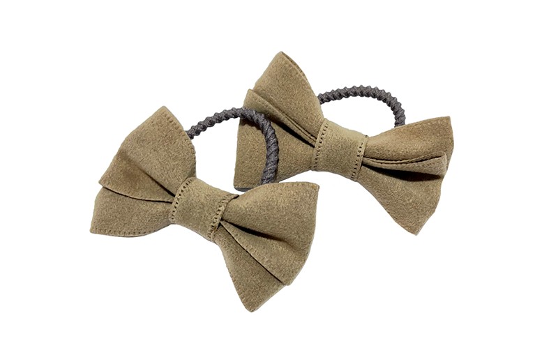 Schattig setje van 2 smalle taupe grijze haarelastiekjes. 
Met op elk een zand kleurig vilten strikje in een mooie dubbelgestrikte look. 
De elastiekjes hebben kleine ribbeltjes waardoor ze beter blijven zitten in de haartjes. 
De strikjes zijn ongeveer 5 centimeter breed.

