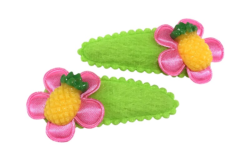 Vrolijk setje van 2 fel groene peuter haarspeldjes. 
Met op elk een fel roze bloemetje en een geel ananas figuurtje. 