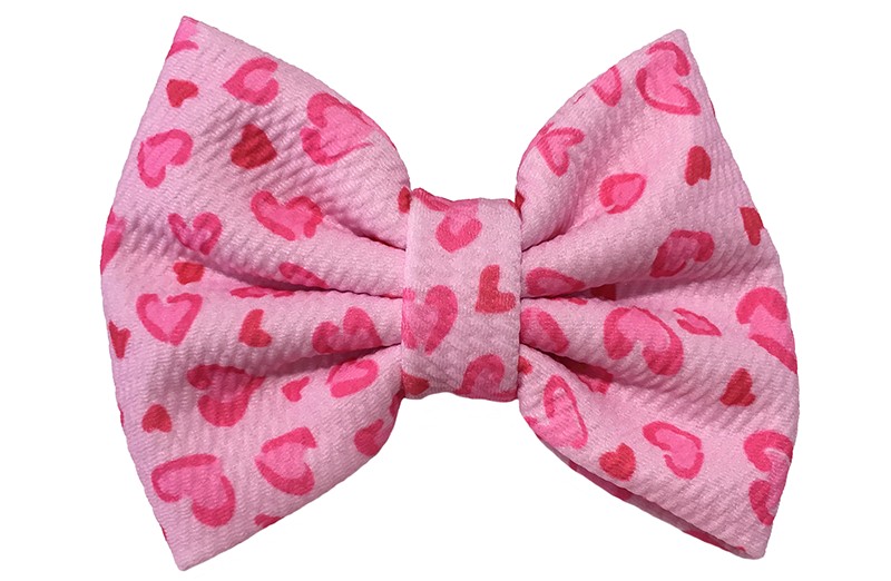 Vrolijke extra grote lichtroze stoffen haarstrik. Met een roze hartjes. 
Op een handige haarknip met kleine tandjes van ongeveer 5.5 centimeter. 